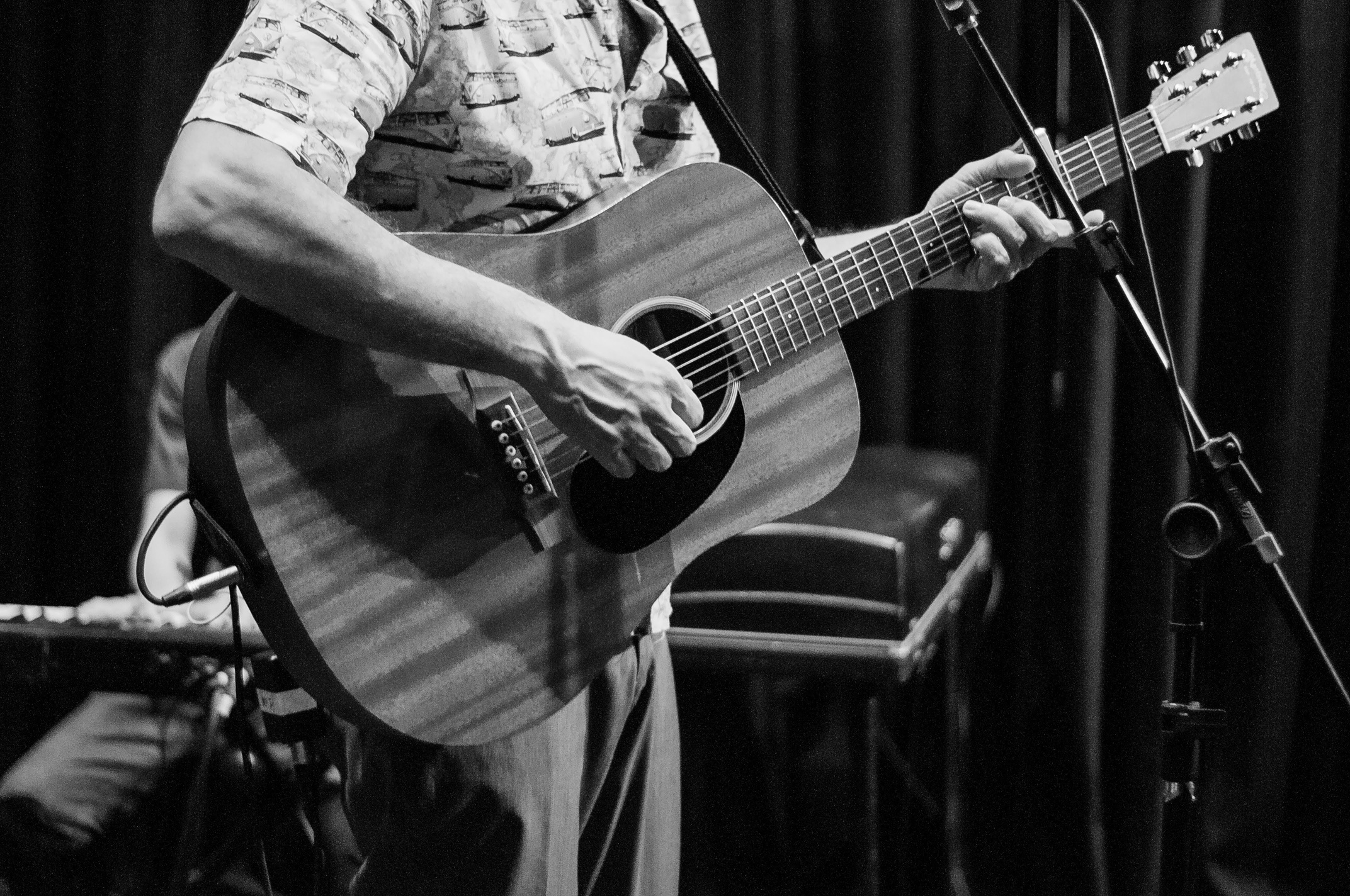 Crop guitarist playing guitar against pianist during musical performance