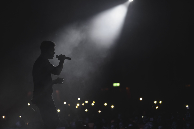 A Man Singing on Stage while Holding a Microphone